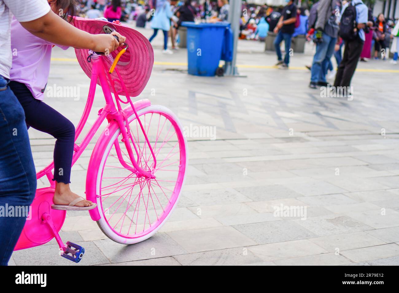 Rosa Ontel Fahrräder mit Kindern, die pinkfarbene Mühlenmützen für Touristen tragen, die vor den Pedalen hängen, sind bei einheimischen Touristen beliebt Stockfoto