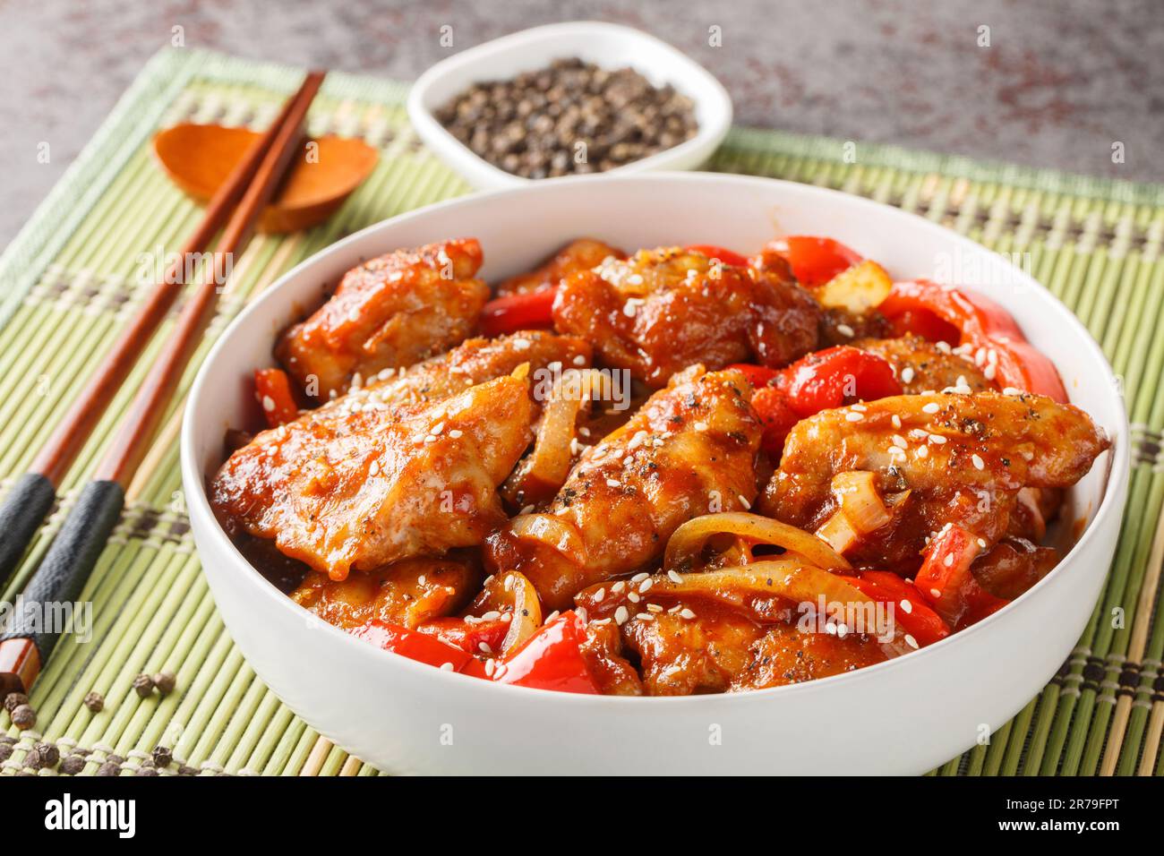 Gebratenes Hähnchen mit Paprika, Zwiebeln, Knoblauch und Ingwer in der Schüssel auf dem Tisch umrühren. Horizontal Stockfoto