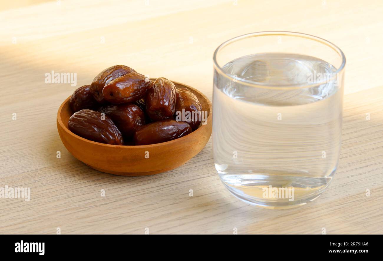 Ramadan iftar Essen, Dattelfrüchte und Glas oder Wasser auf einem Holztisch. Stockfoto