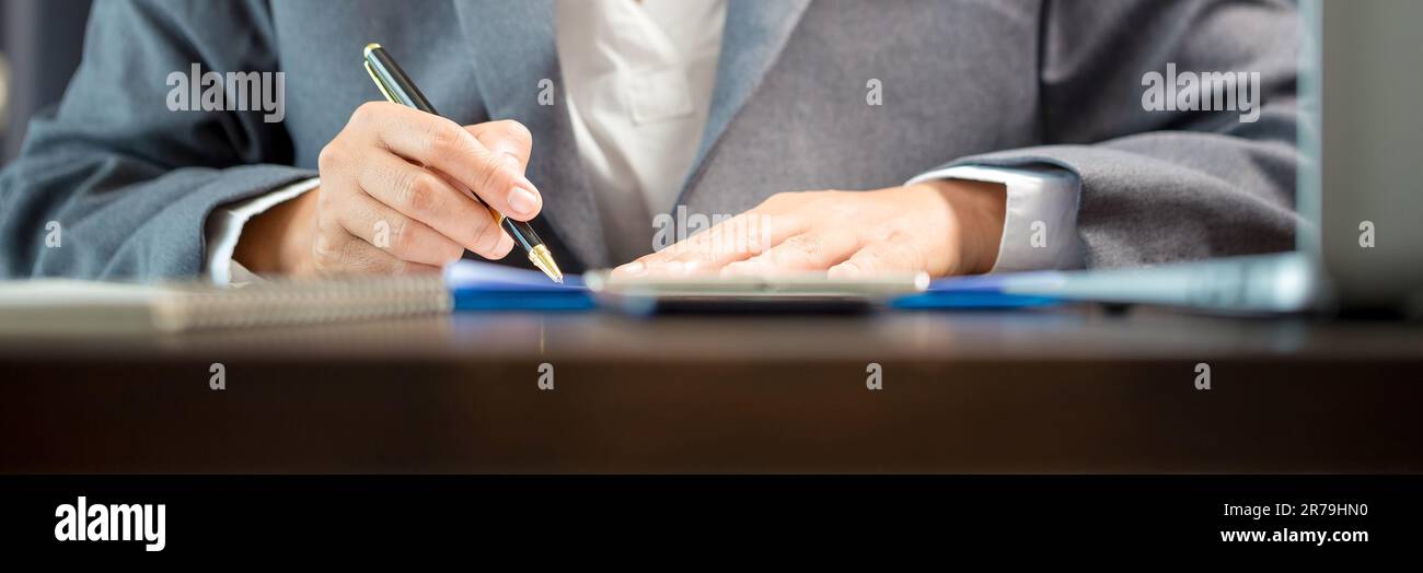 Person für Nahaufnahmen am Arbeitsplatz, professionelle Geschäftsfrau, die am Schreibtisch sitzt, hält eine Unterschrift oder Unterschriftenunterschrift. Angestelltenfrau, die den Vertrag unterzeichnet Stockfoto