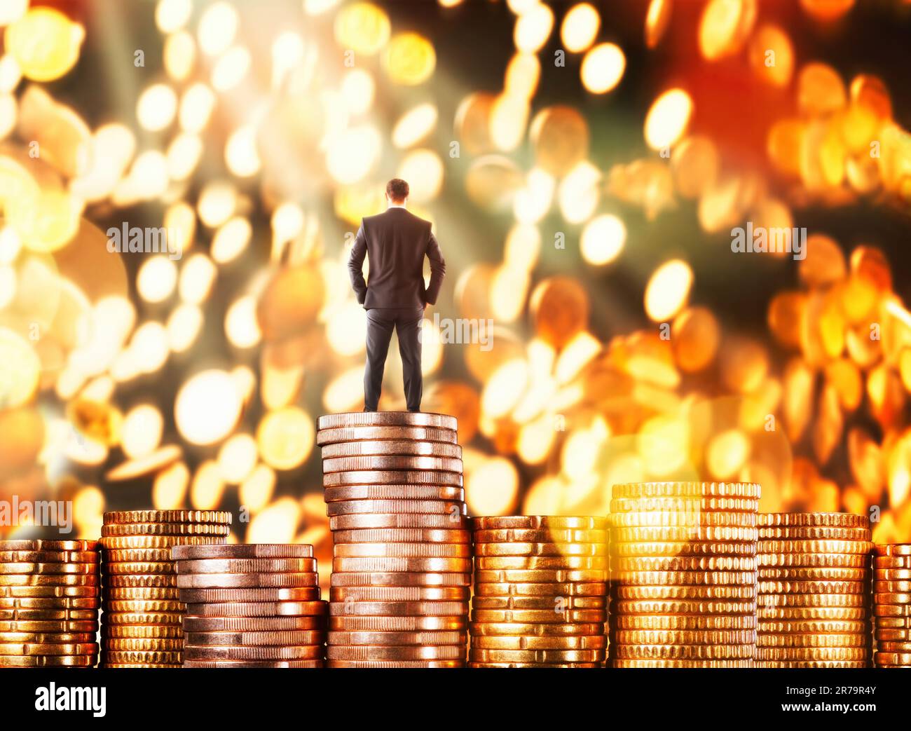 Erfolgreicher Geschäftsmann, der auf Münzen steht und Geld fallen lässt Stockfoto