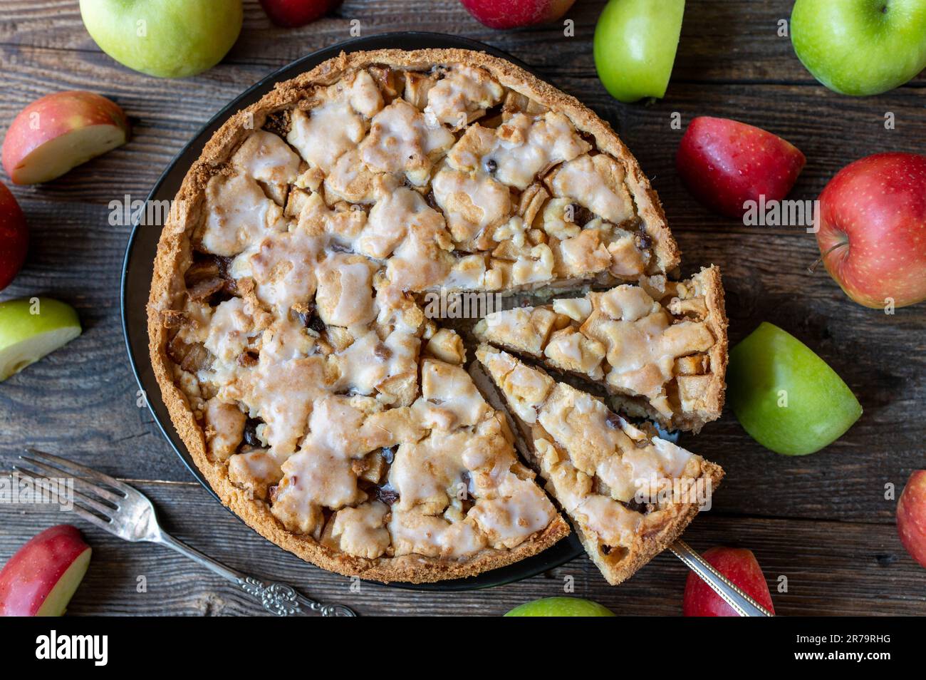 Ganzer und runder Apfelkuchen, gebacken mit kurzer Kruste, vorgekochten Äpfeln, Zimt und Rosinen. Garniert mit einer köstlichen Zitronenglasur Stockfoto