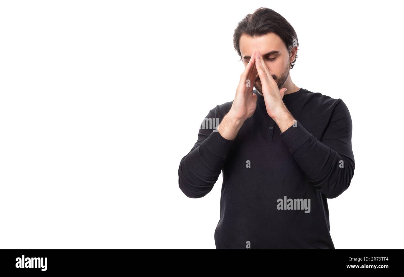 Ein hübscher, brutaler europäischer Macho-Mann mit schwarzem Haar und Bart mit Ohrring im Ohr hofft und betet auf Glück auf einem isolierten weißen Backen Stockfoto