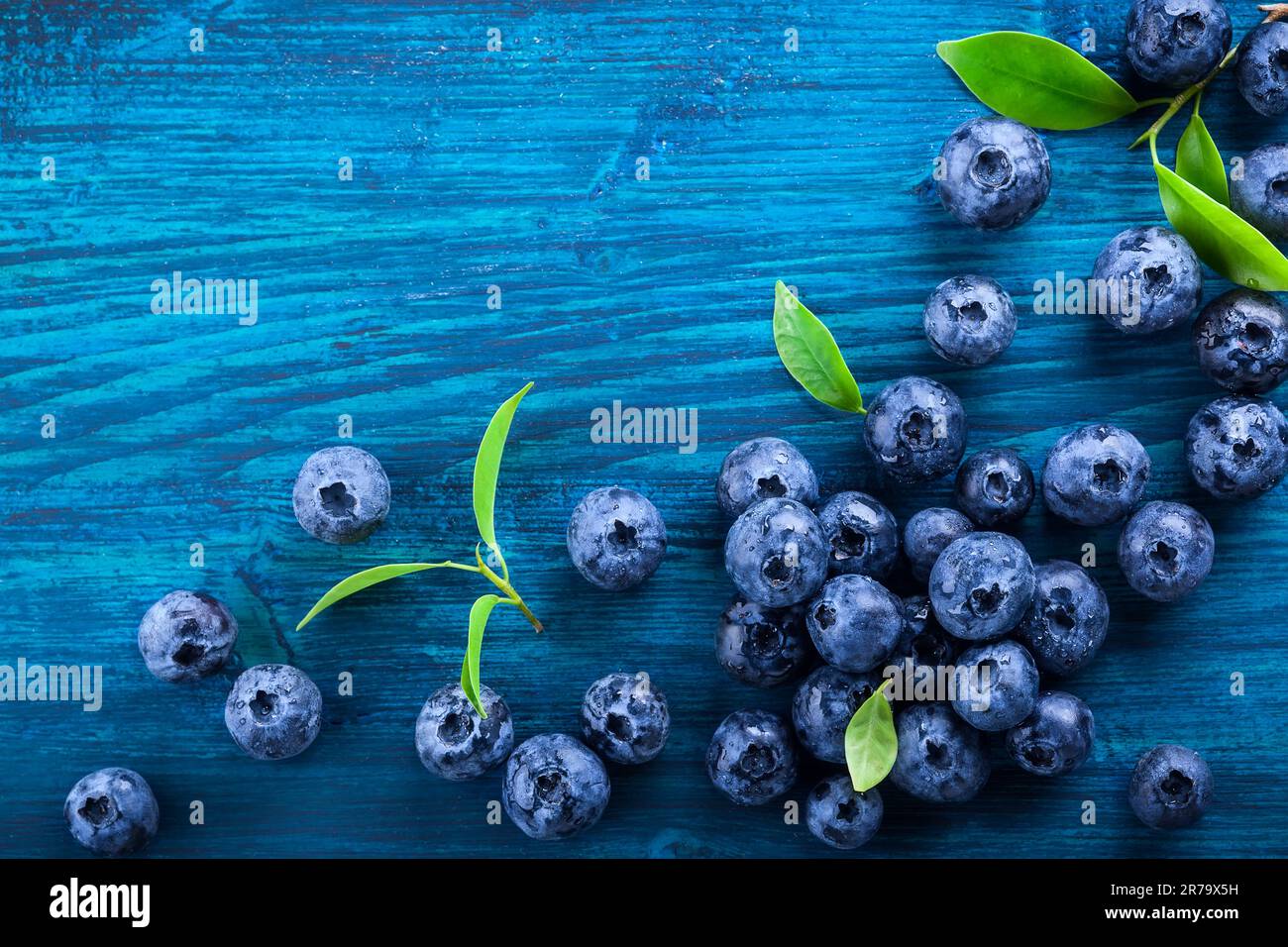 Frische Heidelbeeren mit Wassertropfen auf Blau Holz- Hintergrund. Ansicht von oben. Konzept der gesunde und nährende Essen Stockfoto