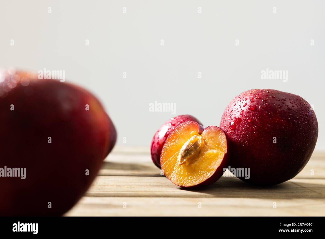 Nahaufnahme frischer nasser Pfirsiche auf einem Holztisch vor weißem Hintergrund, Kopierbereich Stockfoto