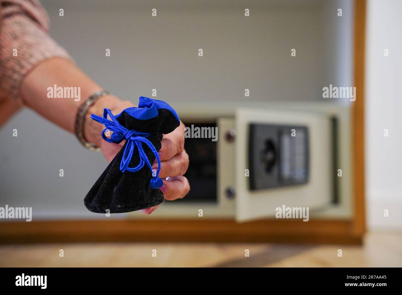 Eine Hand legt Schmuck in einen Hotelsafe Stockfoto