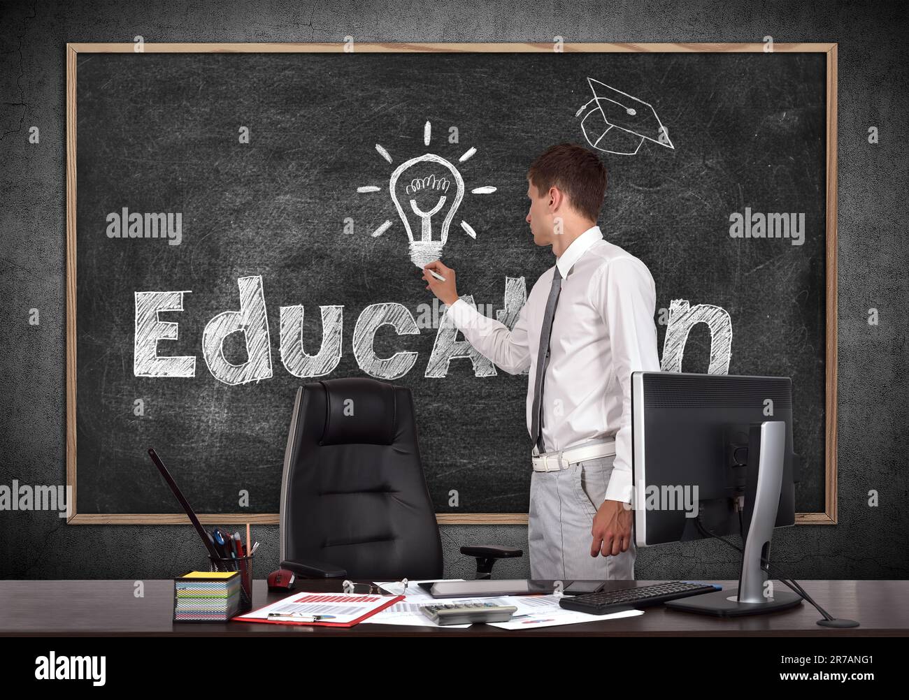 Geschäftsmann im Büro zeichnet Bildungs-Symbol auf der Tafel Stockfoto