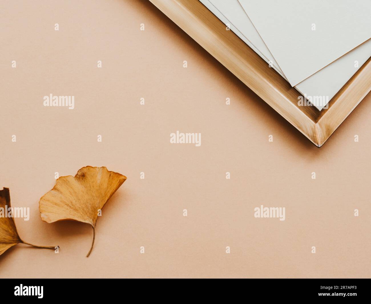 Minimale ästhetische Zusammensetzung mit goldenem Tablett und weißeren Karten und zwei gelben Blättern auf beigefarbenem Hintergrund. Leerer Bereich für Text. Minimalistischer, moderner Stil Stockfoto