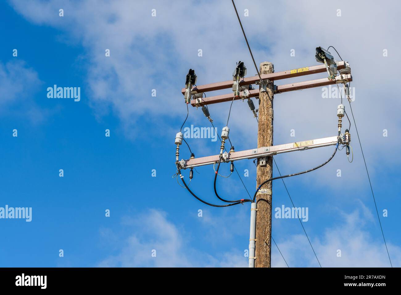 Nahaufnahme eines Holzpfostens zur Unterstützung von Hochspannungskabeln an einem sonnigen Herbsttag Stockfoto