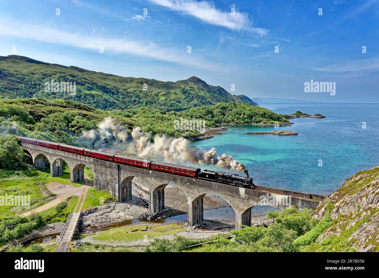 Jacobite Steam Train überquert das Nan Uamh Viadukt im Frühsommer mit blauem grünen Wasser des Loch Nan Uamh an der Westküste Schottlands Stockfoto