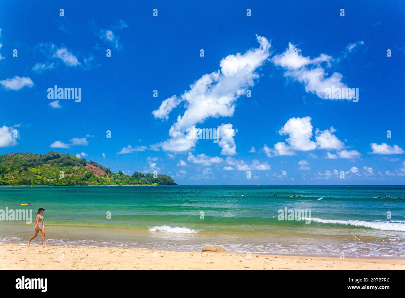 Eine Frau, die an einem sonnigen tropischen Strand spaziert Stockfoto