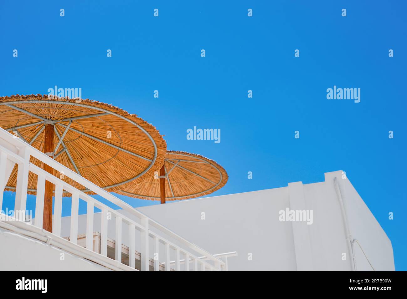 Sonnenschirme auf dem Dach des Hauses vor dem blauen Himmel, die griechische Straße im Einkaufszentrum Lindos, die Insel Rhodos, die griechischen Inseln Th Stockfoto