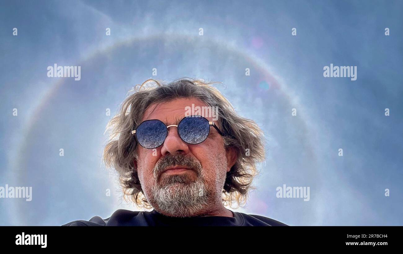 Selbstporträt mit Smartphone, im Hintergrund die Sonne mit Halo-Effekt, die durch die Reflexion und Refraktion von Licht auf Eiskristallen verursacht wird Stockfoto