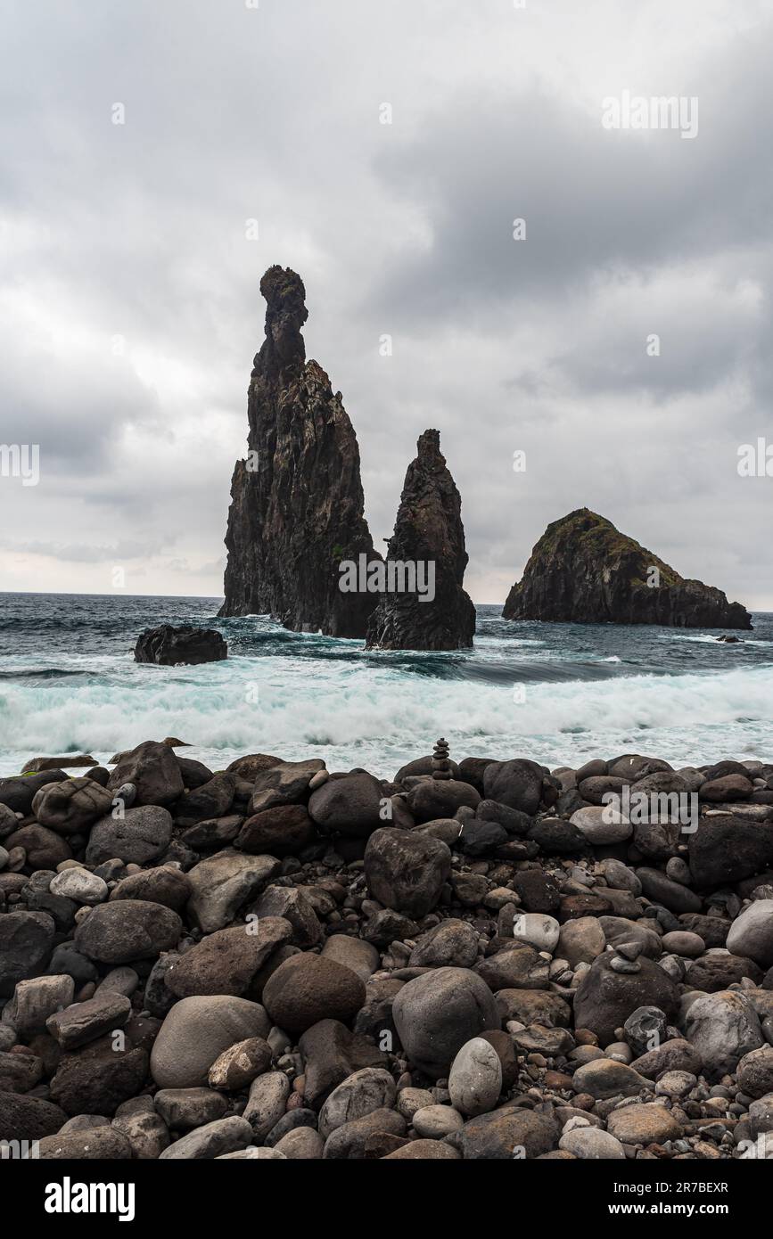 Steine an der Küste und wilder Atlantik mit kleinen felsigen Inseln in der Nähe von Ribeira da Janela auf Madeira Stockfoto