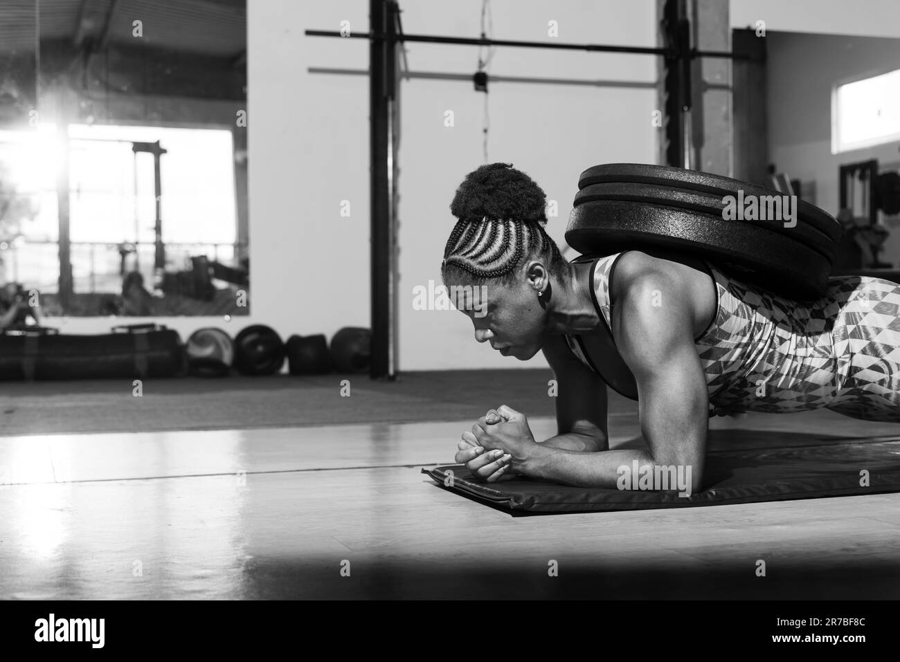 Eine sportliche Fitness-begeisterte Frau, die sich an einer gewichteten Plankübung beteiligt und Kraft, Gleichgewicht und Entschlossenheit demonstriert Stockfoto