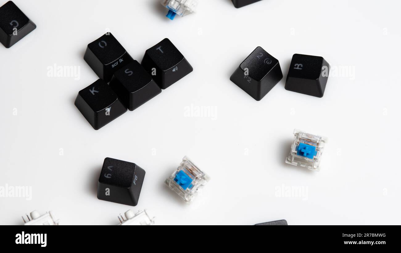 Verstreute Tastenkappen und Schlüsselschalter für mechanische Tastaturen auf weißem Hintergrund Stockfoto