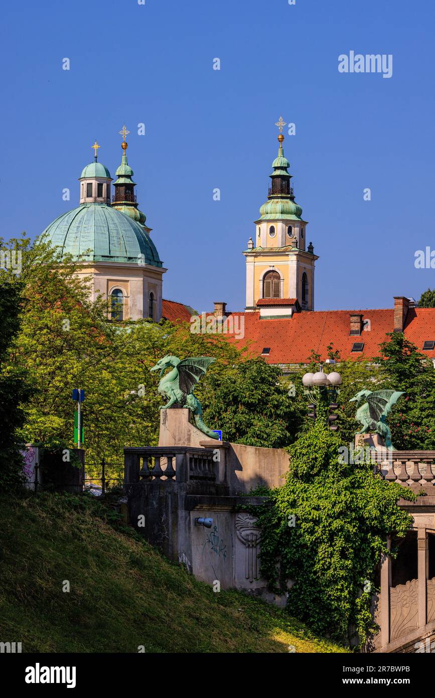 Die grünen Kuppeln der kathedrale von ljubljana über der grünen Drachenstatue auf der berühmten Drachenbrücke von ljubljana Stockfoto