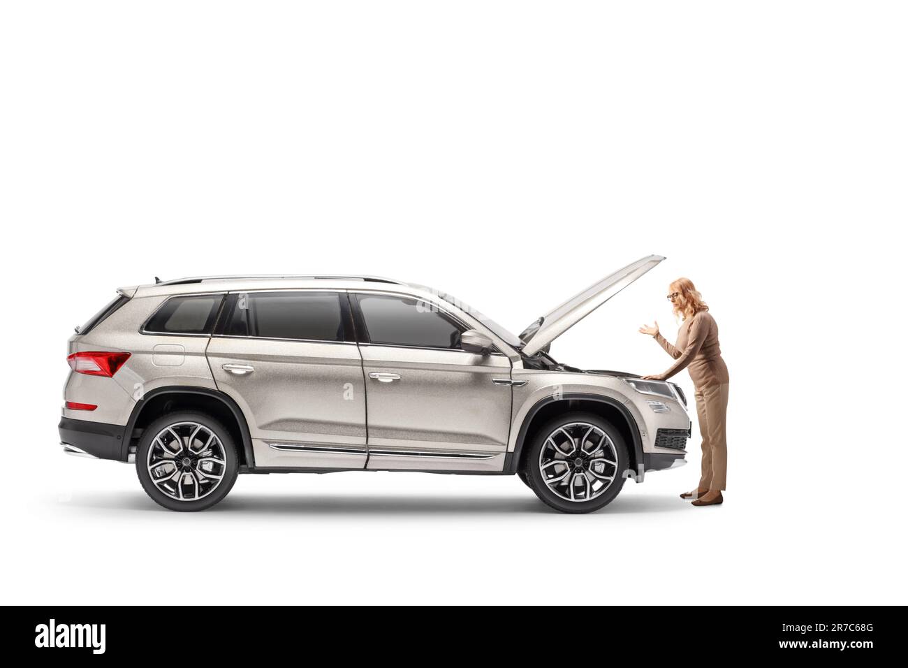 Verwirrte Frau mit Autoproblem, die den Motor isoliert auf weißem Hintergrund betrachtet Stockfoto