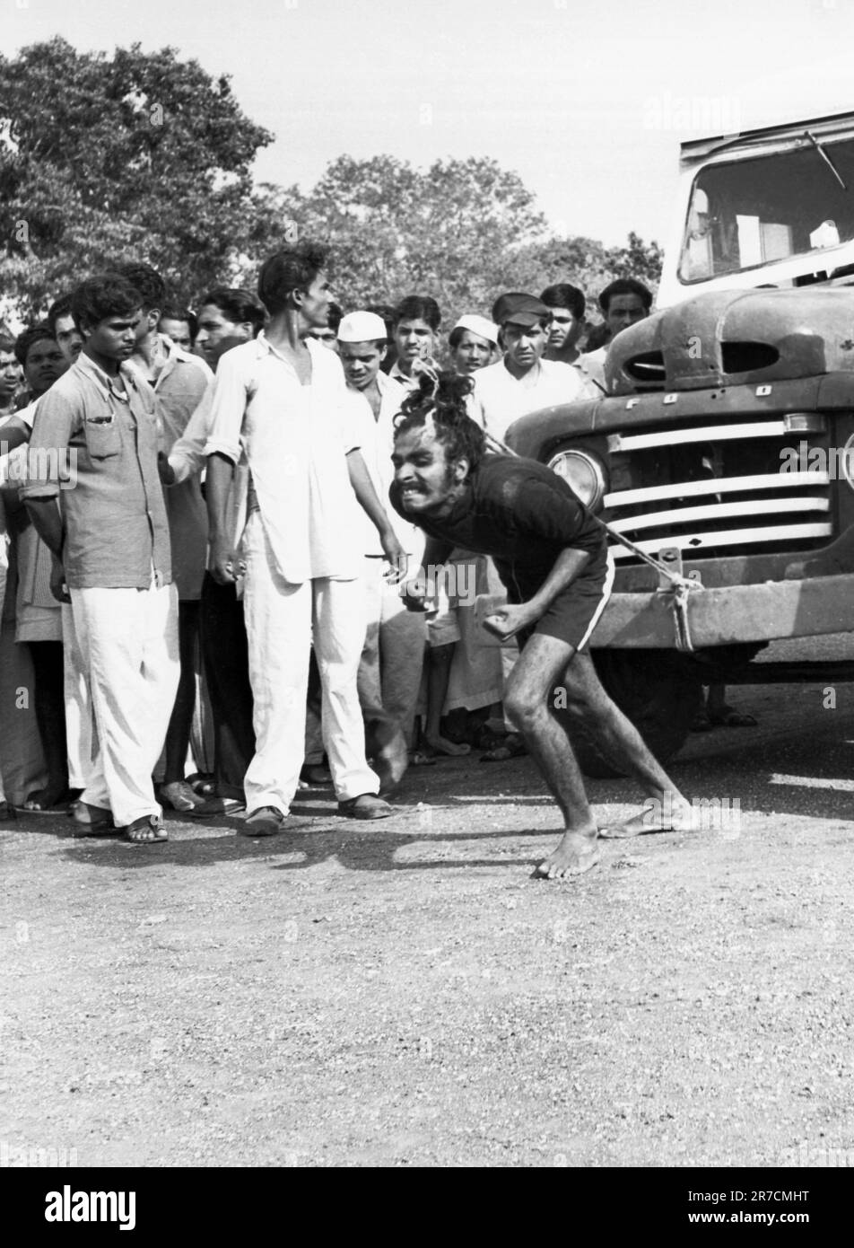 Indien: ca. 1970 Ein Mann überanstrengt sich, einen Truck mit seinen Haaren zu ziehen. Stockfoto
