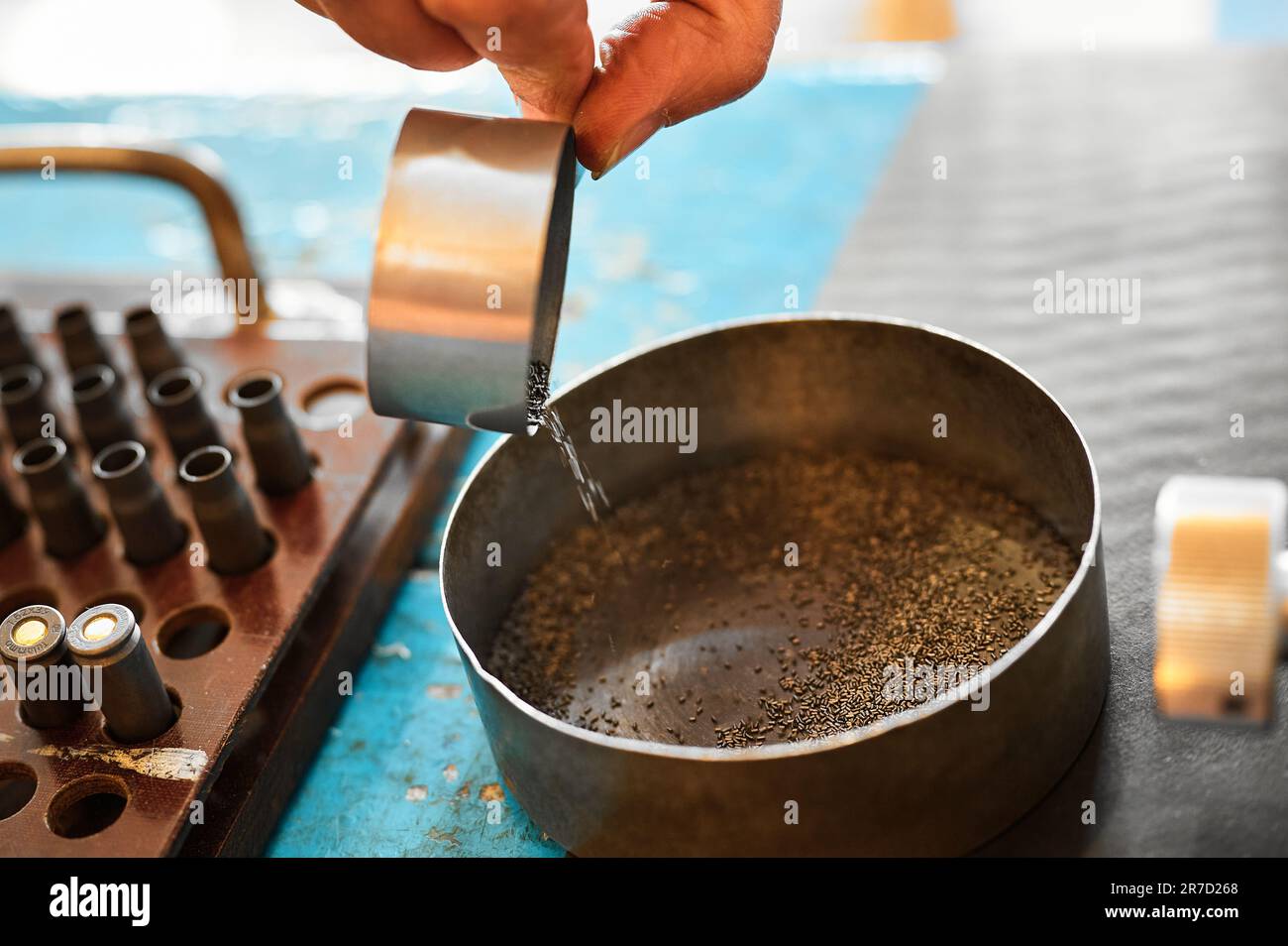 Arbeiter schüttet Schießpulver in die Metallschüssel auf dem Tisch in der Fabrik Stockfoto