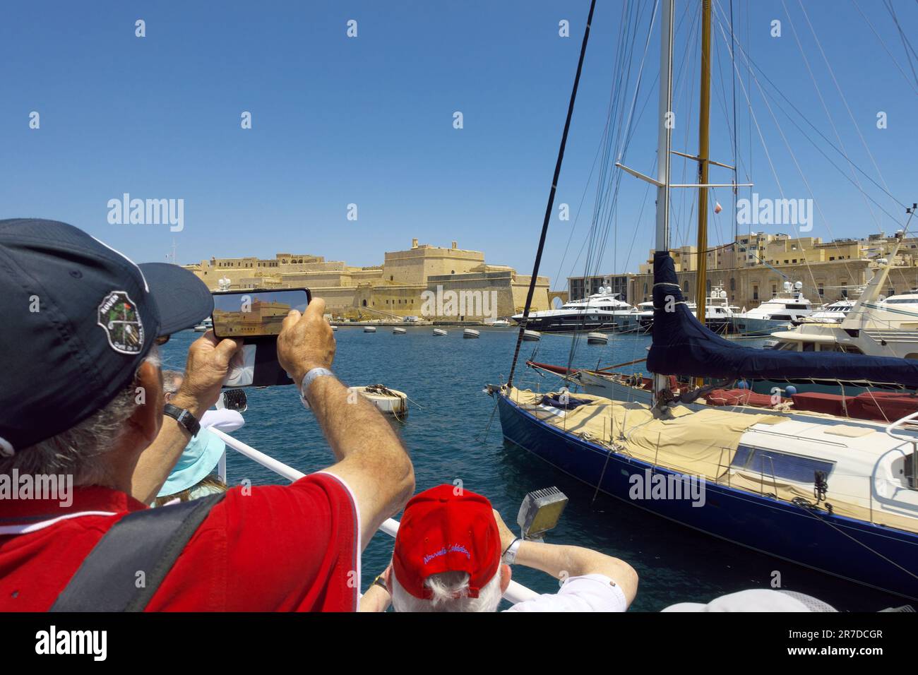 Ein Mann, der ein Foto von Fort St. macht Angelo von der Fähre in Senglea, Malta Stockfoto