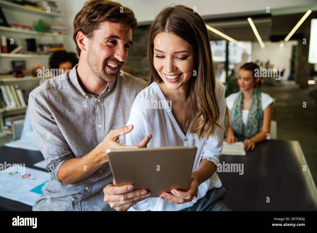 Lächelnd treffen sich verschiedene Kollegen in einem Brainstorming in der Vorstandsetage, um gemeinsam Finanzstatistiken zu diskutieren Stockfoto