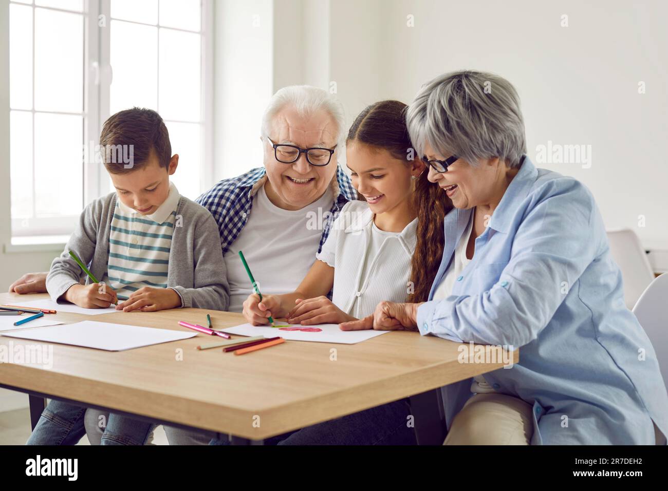 Liebe reife Großeltern, die Enkelkindern bei Hausaufgaben zu Hause helfen Stockfoto