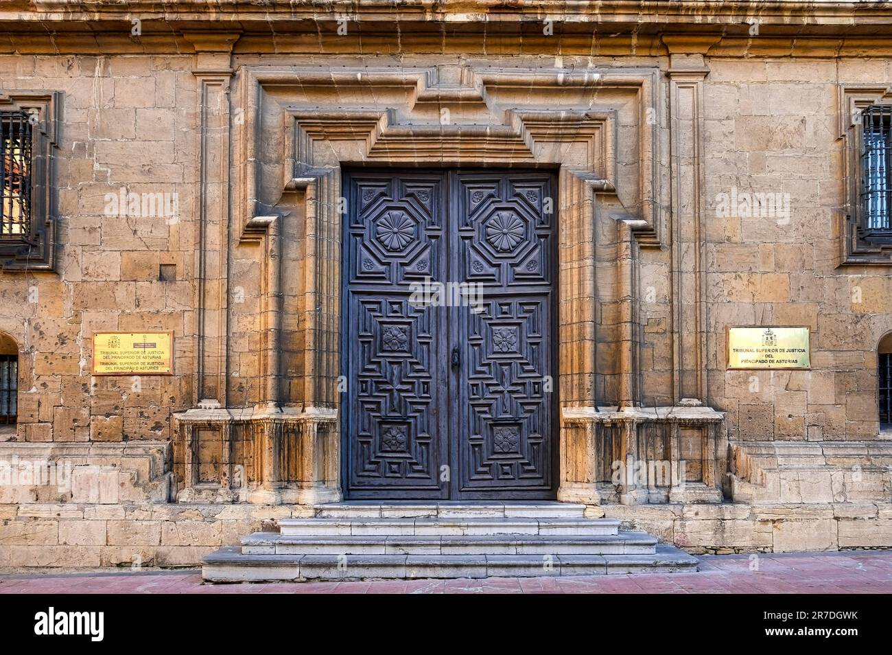 Oviedo, Asturien, Spanien - 12. Februar 2023: Backsteingebäude mit kunstvollem Eingang, Treppe und geschlossener Metalltür. Die Fassade zeigt i an Stockfoto