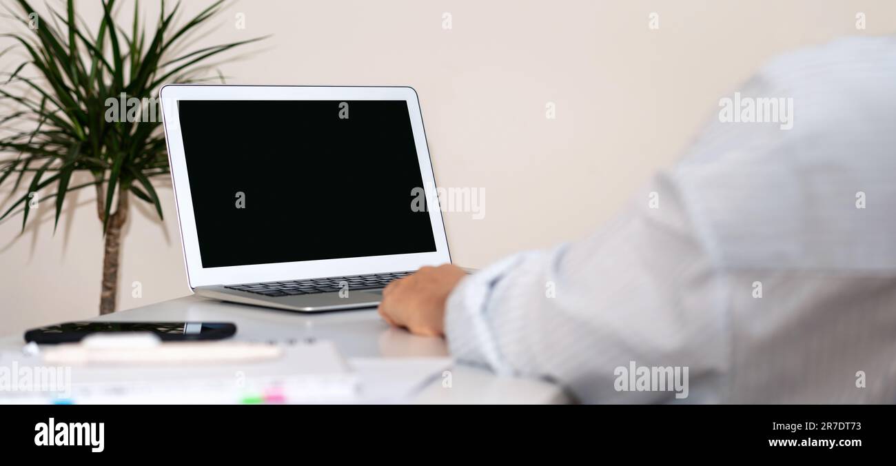 Nicht wiedererkennbarer Geschäftsmann, der an einem Laptop arbeitet, mit leerem Bildschirm auf dem Schreibtisch im Büro Stockfoto