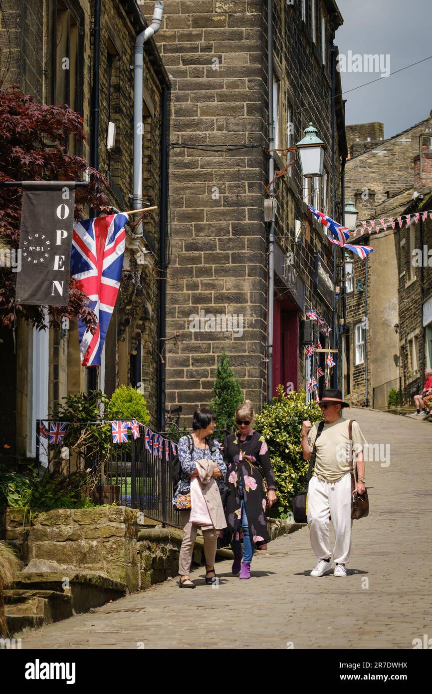 Haworth, West Yorkshire, Großbritannien. Drei Besucher von Haworth machen einen Spaziergang entlang der Main Street in diesem beliebten Dorf in West Yorkshire. Stockfoto