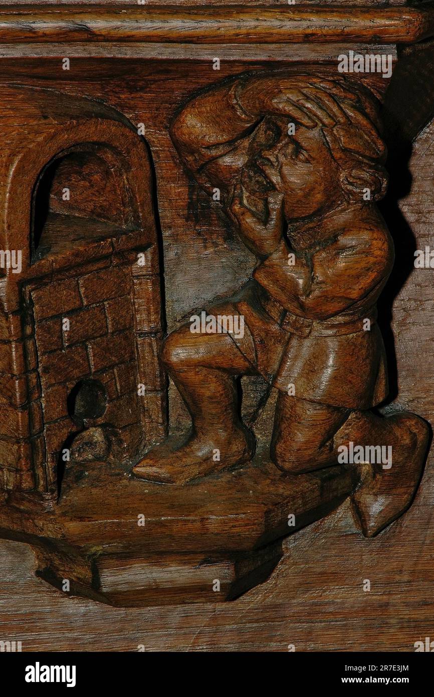 Versuchen Sie nicht das Unmögliche. Es ist, als würde man versuchen, breiter zu gähnen als eine Ofentür. Ein altes Sprichwort, das Ende der 1400s Jahre als hölzerner Misericord geschnitzt wurde, unter einem Chorplatz in der Oude Kerk oder der Alten Kirche in Amsterdam, Niederlande, Stockfoto