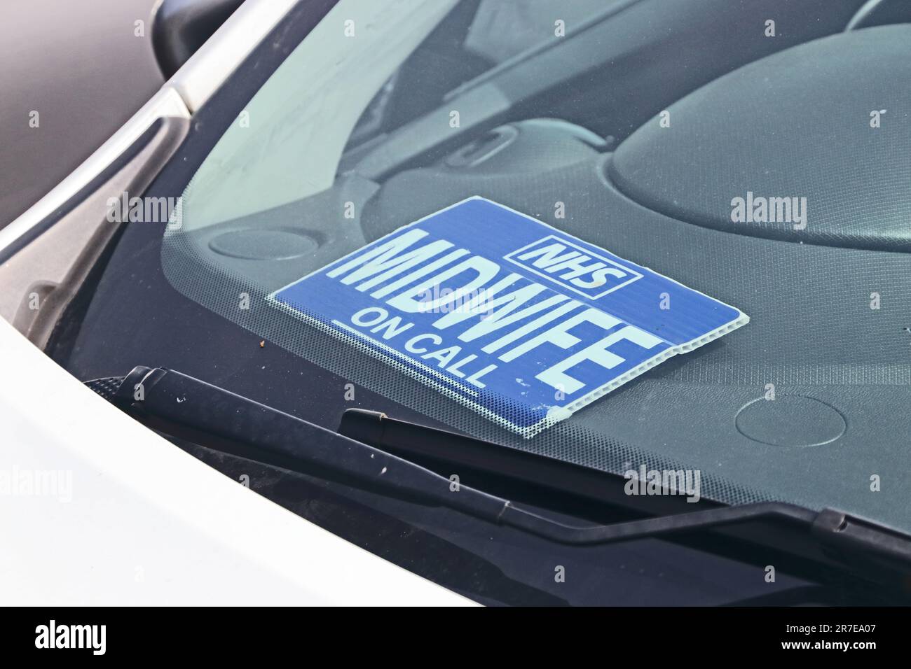 NHS Midwife On Call-Schild auf dem Armaturenbrett des geparkten Autos Stockfoto