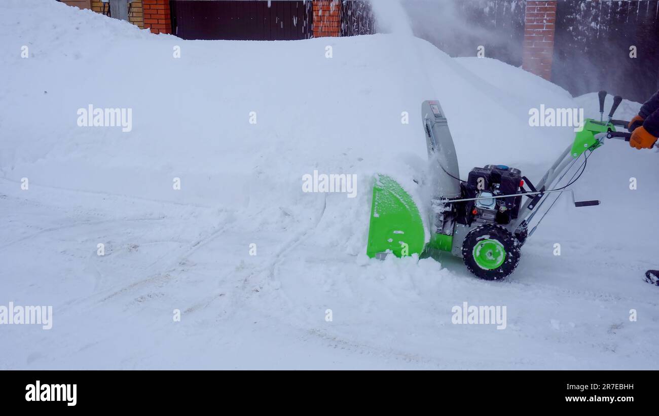 Ein Mann reinigt im Winter Schnee im Hof des Hauses. Ein Mann, der Schnee  mit einer Schneefräse reinigt Stockfotografie - Alamy