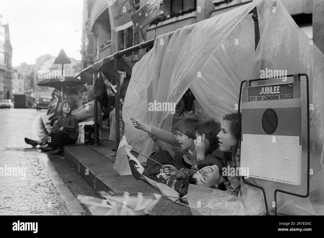 Queen Elizabeth II. Silberjubiläum 1977. Die Wunschfreunde warten die ganze Nacht und gießen oft Regenschutz unter Sonnenschirmen und Plastikdecken für die Silver Jubilee Royal Prozession am nächsten Morgen. London, England, etwa Juni 1977. Stockfoto