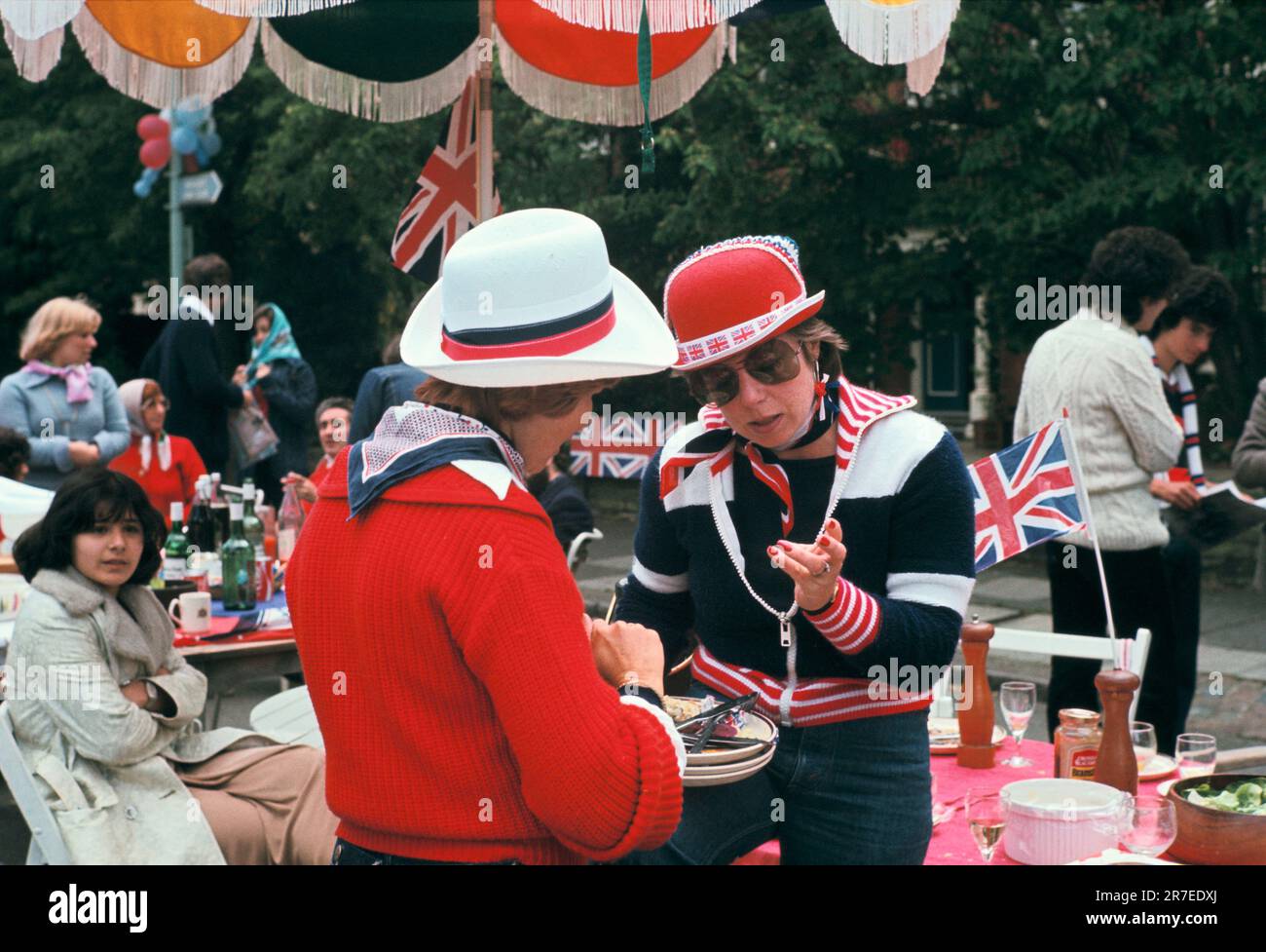 Queen Elizabeth II. Silberjubiläumsfeier 1977. Silber-Jubiläum-Straßenparty, zwei Frauen in Rot, Weiß und Blau-Chat. Hampstead, Nord-London, England, ca. Juni 1977. Stockfoto