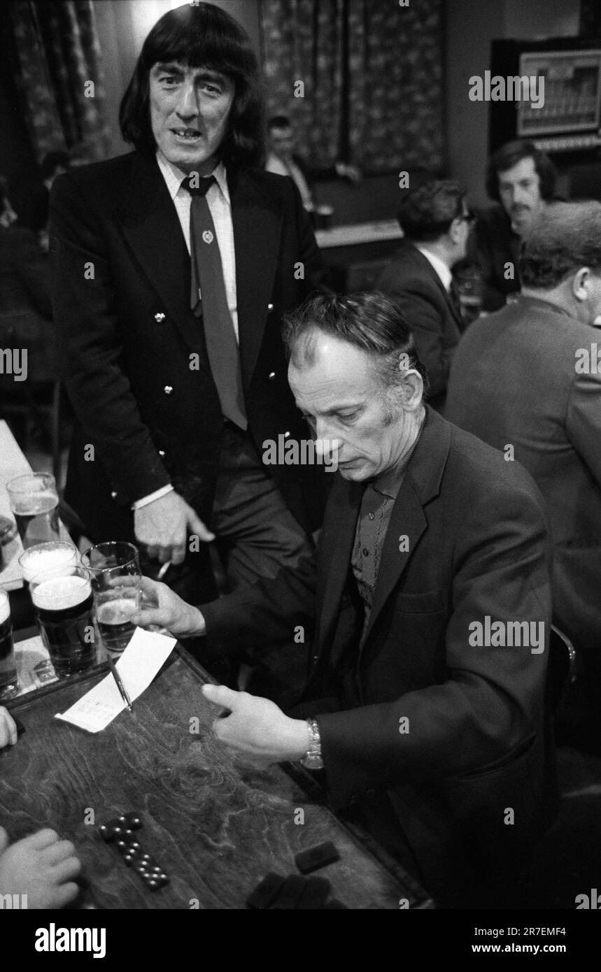 Samstagabend spielt man Dominospiele im Byker and St Peters Working Men's Social Club. Typisch Männer, die sich für den Abend verkleidet haben. 1970er Fashion, ein Beatles-Haarschnitt ( im Stil von John, Paul, George und Ringo ) ein blauer zweireihiger Blazer mit Messingknöpfen, Kragen und Krawatte. Newcastle Upon Tyne, Tyne und Wear, Nordengland um 1973. 1970S GB HOMER SYKES Stockfoto