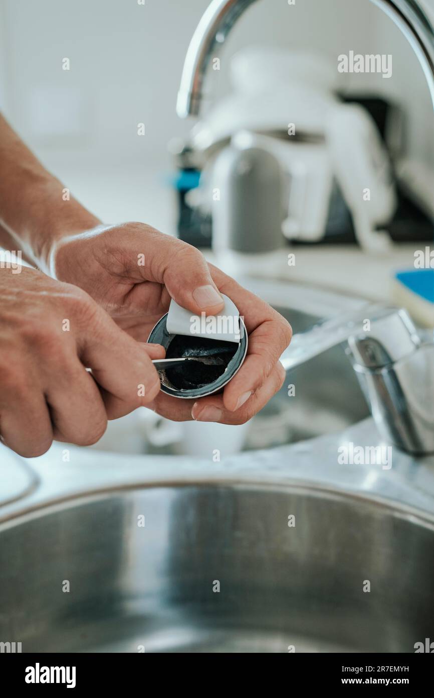 Ein weißer Mann in der Küche leert den gebrauchten gemahlenen Kaffee einer Kapsel, um die Kapsel zu recyceln Stockfoto