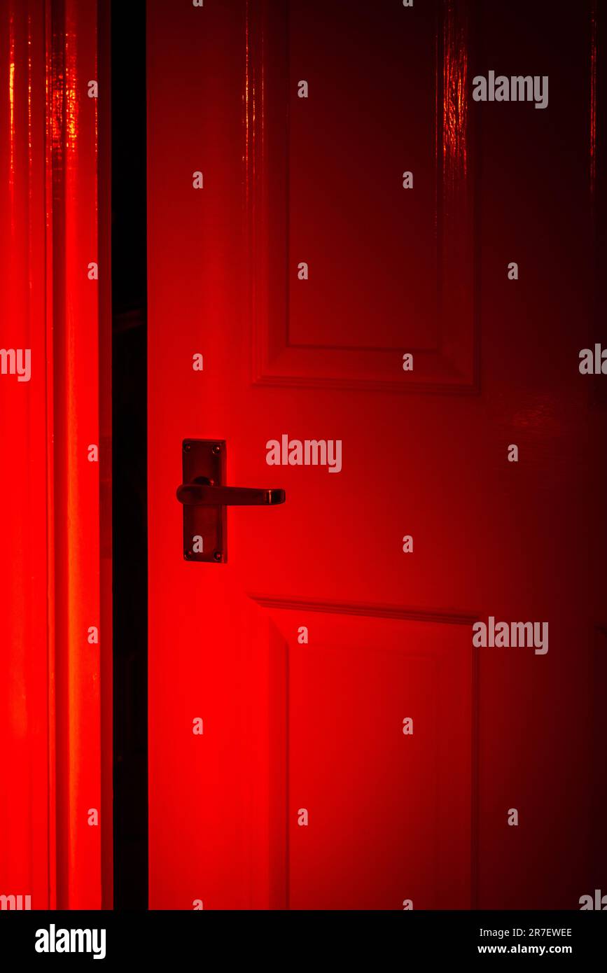 Öffnete die Tür mit rotem Licht, das darauf leuchtete - rotes mysteriöses Rampenlicht Stockfoto