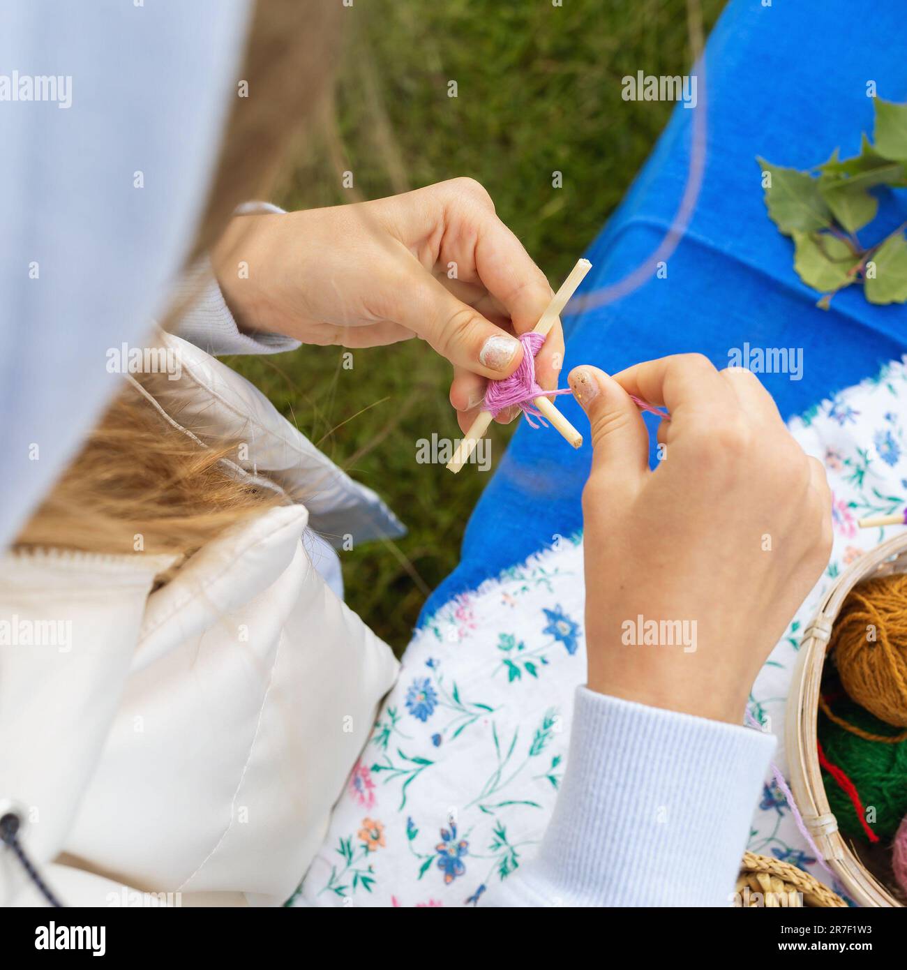 Ein Kind macht ein traditionelles Amulett, das Rowan-Kreuz genannt wird, eine alte russische Volkstradition Stockfoto