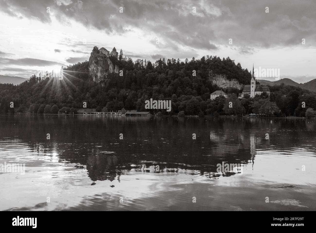 Schwarzweiß-Bild eines Sonnenaufgangs bei Sonnenuntergang, das eine wunderschöne Szene mit einer blutigen Burg und St. martins Kirche darstellt, die sich in einem blutigen See widerspiegelt Stockfoto