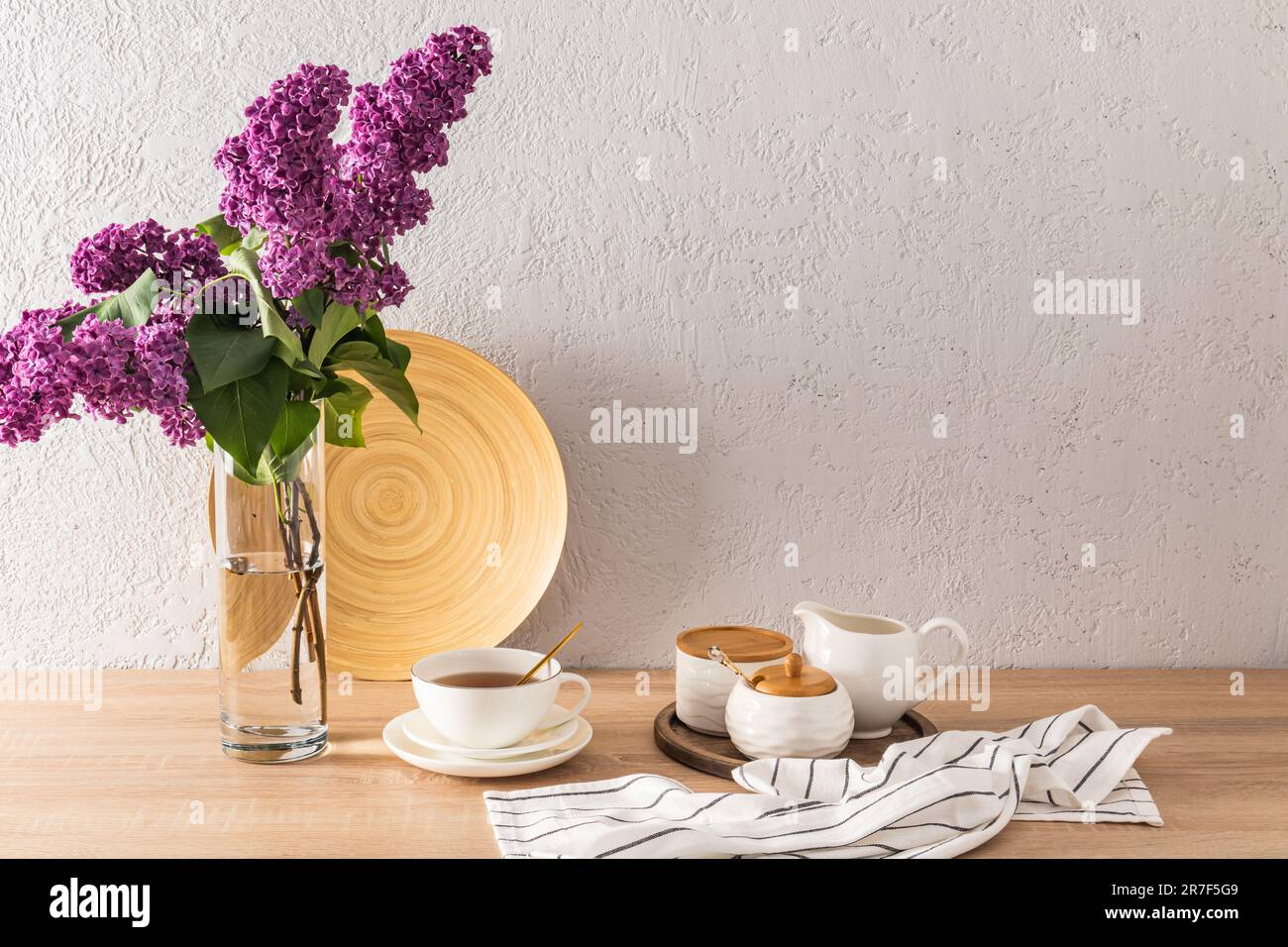 Eine Tasse Morgentee und Teeutensilien auf einer umweltfreundlichen Küchenarbeitsfläche und einer Blumenvase. Vorderansicht. Minimalistischer Style Stockfoto