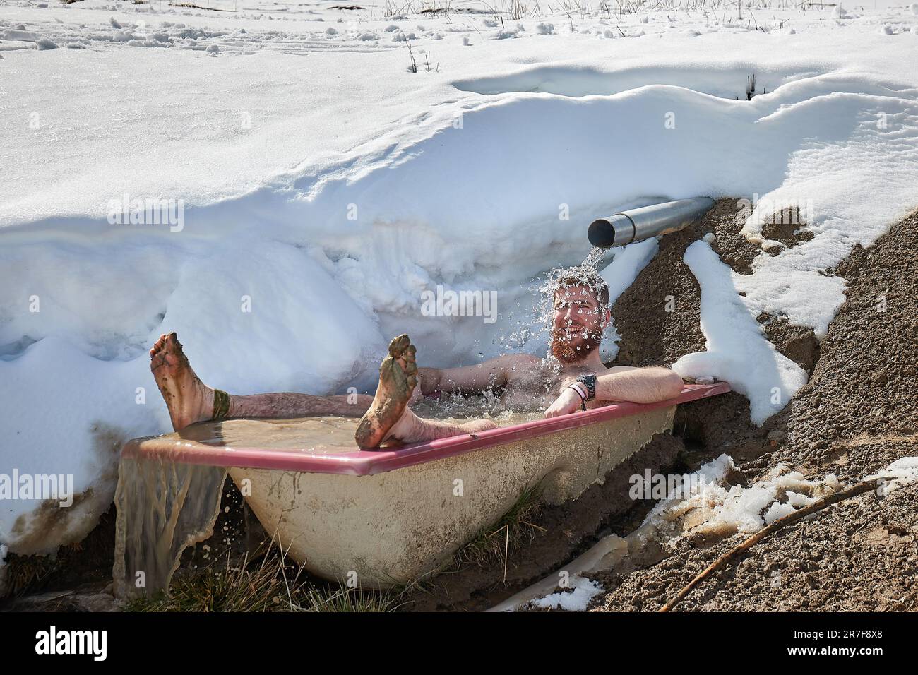 Ein Mann, der in einer verschneiten Badewanne kalte Bahnen taucht Stockfoto