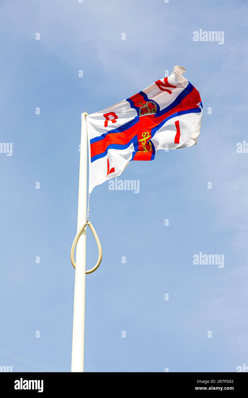 Die Flagge der Royal National Lifeboat Institution RNLI, die an der Rettungsbootstation in St. Justinians, Pembrokeshire, Wales, Großbritannien, tapfer fliegt Stockfoto