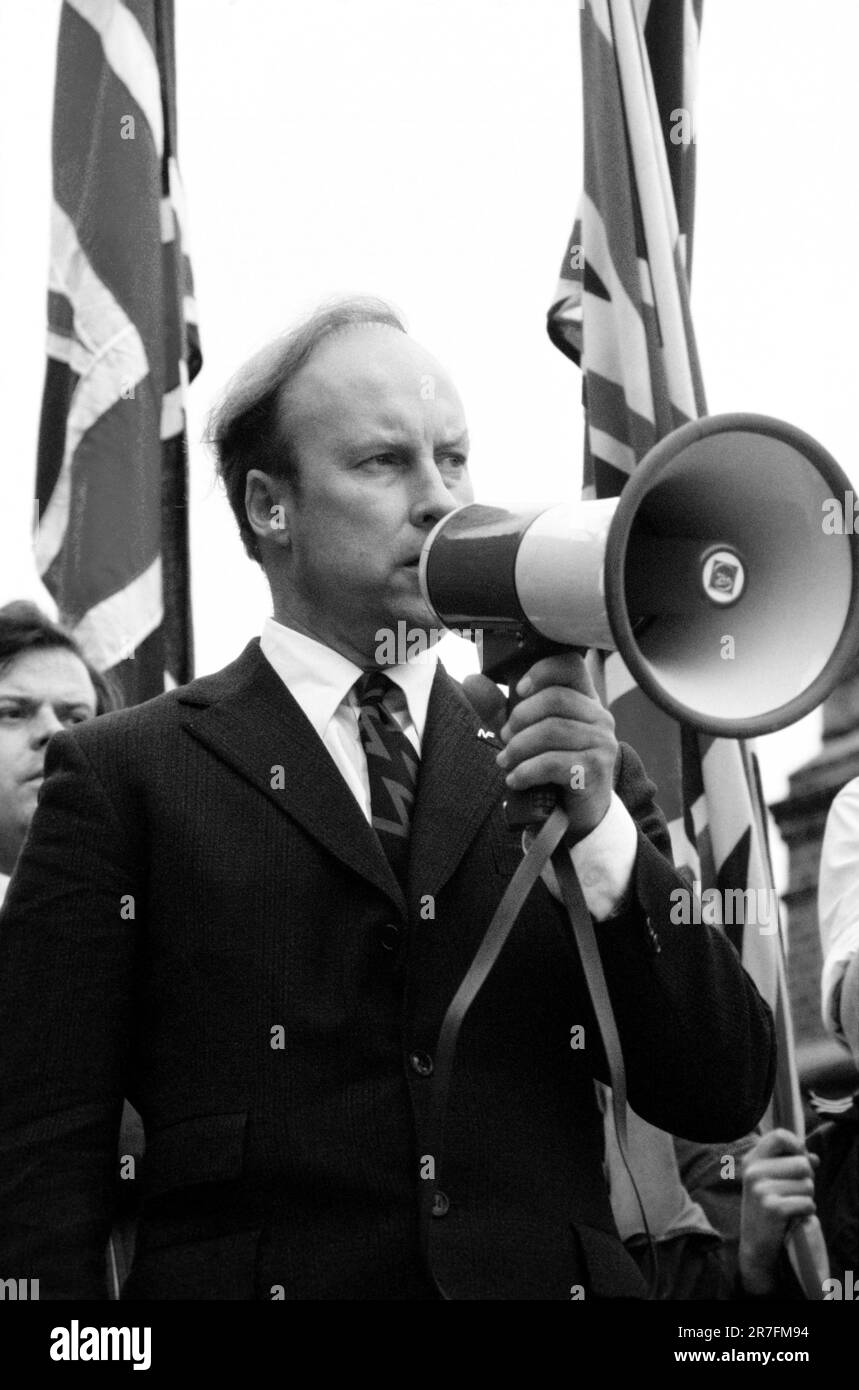 John Tyndall, Anführer der Front National, Lewisham, London.1977 die Polizei beschützt Mitglieder der Front National während der so genannten Schlacht von Lewisham, die am 13. August stattfand. 500 Mitglieder der Nationalen Front marschierten vom Neuen Kreuz nach Lewisham, verschiedene Gegendemonstrationen von etwa 4.000 Personen führten zu gewaltsamen Auseinandersetzungen zwischen den beiden Gruppen sowie zwischen den Anti-NF-Demonstranten und der Polizei. GROSSBRITANNIEN 1970ER JAHRE HOMER SYKES Stockfoto