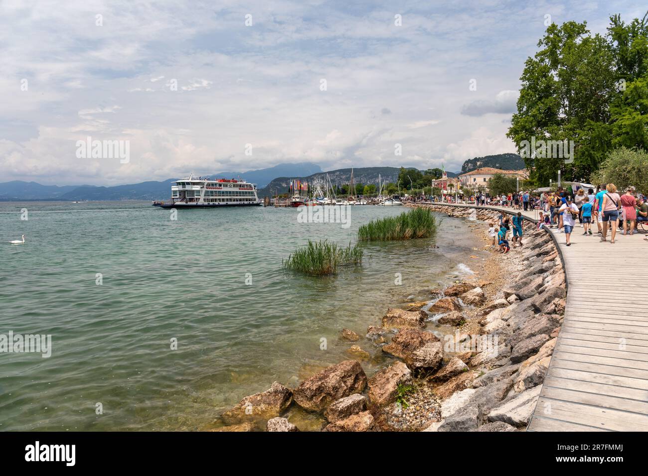 Tonal Ferry Ankunft in Bardolino, während Touristen entlang der Promenade, Bardolino, Gardasee, Italien, Europa spazieren Stockfoto