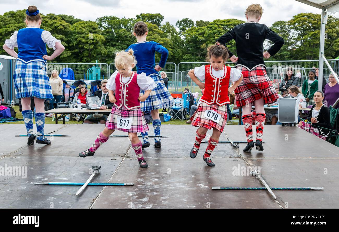 Junge Mädchen, die bei einem Highland-Schwert-Tanz in traditionellen schottischen Kleidern Kilts, Highland Games, North Berwick, Schottland, Großbritannien, gegeneinander antreten Stockfoto