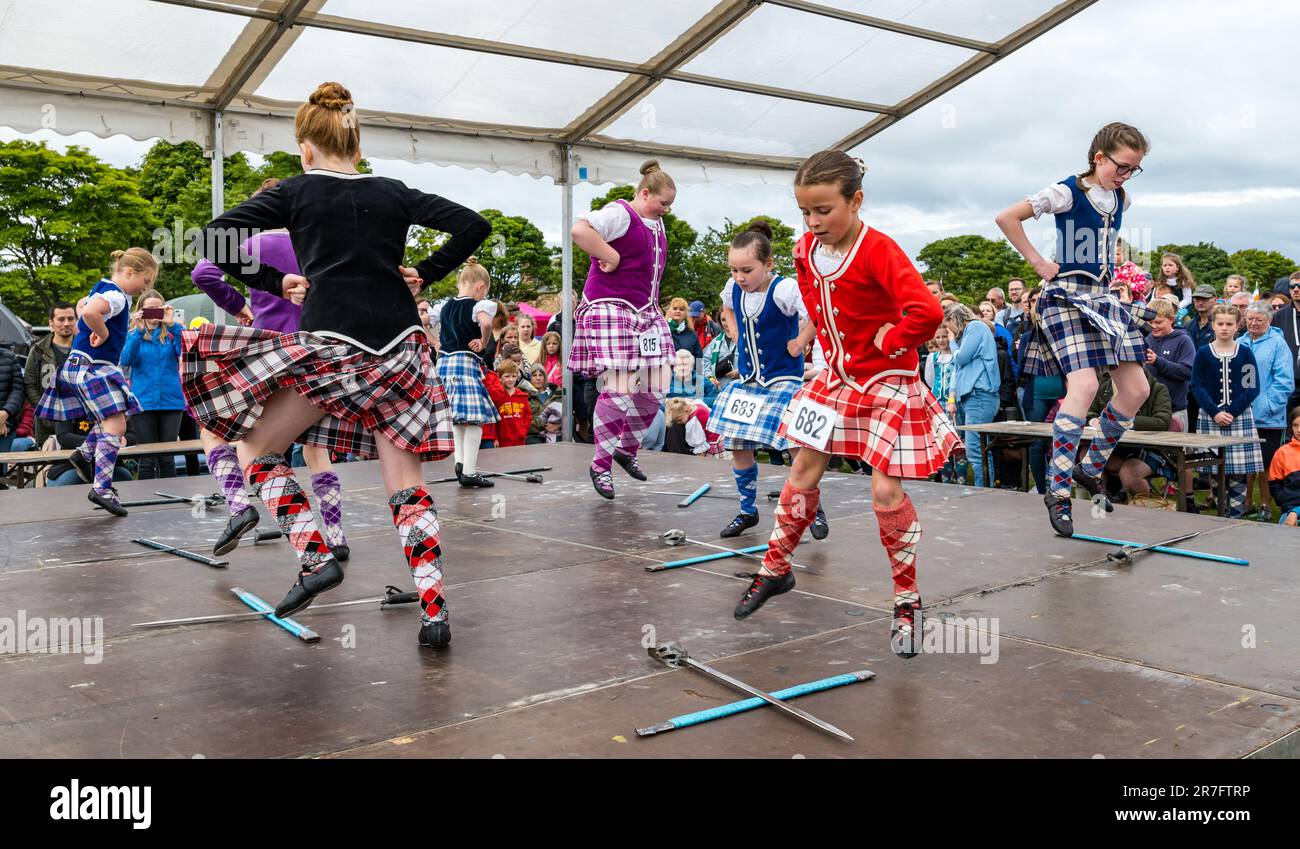 Junge Mädchen, die bei einem Highland-Schwert-Tanz in traditionellen schottischen Kleidern Kilts, Highland Games, North Berwick, Schottland, Großbritannien, gegeneinander antreten Stockfoto