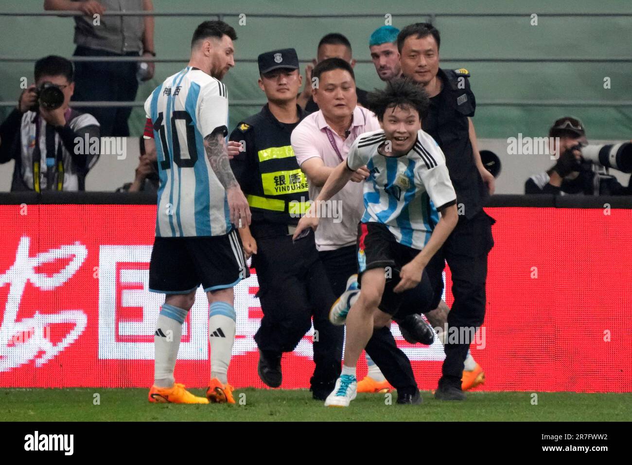 Argentina's Lionel Messi, left, watches as security officers pursue a fan during play on the field in their friendly soccer match against Australia at Workers' Stadium in Beijing, Thursday, June 15, 2023. (AP Photo/Mark Schiefelbein) Stockfoto