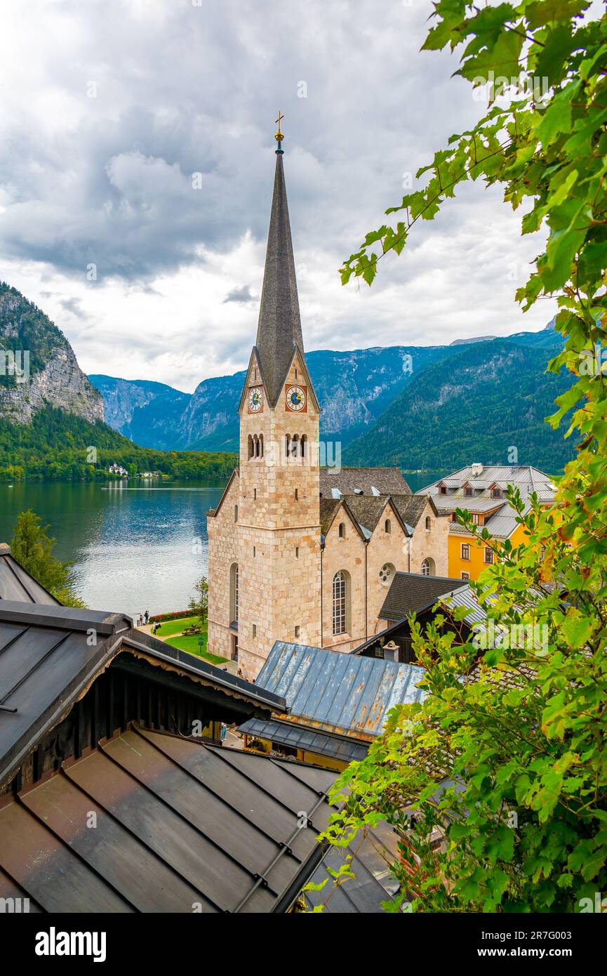 Das berühmte Stadtpanorama Hallstatt mit einer typischen Kirche in der Nähe des Hallstatter Sees. Dramatische Wolken am Himmel. Berühmtes Touristenziel in Österreich. Stockfoto