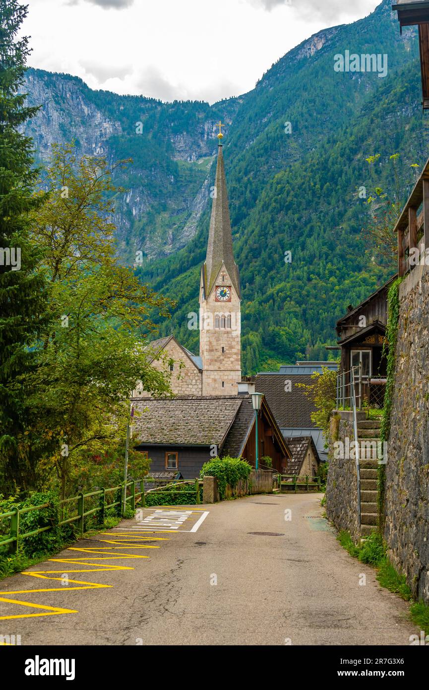 Das berühmte Stadtpanorama Hallstatt mit einer typischen Kirche in der Nähe des Hallstatter Sees. Dramatische Wolken am Himmel. Berühmtes Touristenziel in Österreich. Stockfoto